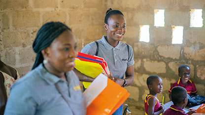Two Intertek volunteers smiling while in a classroom with young children